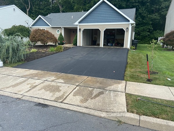 Freshly sealcoated asphalt driveway at a two-car garage home by R. Stanley's Paving.