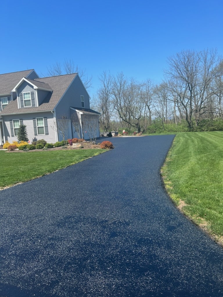 Long freshly sealcoated asphalt driveway at a home in Berks County by R. Stanley's Paving.